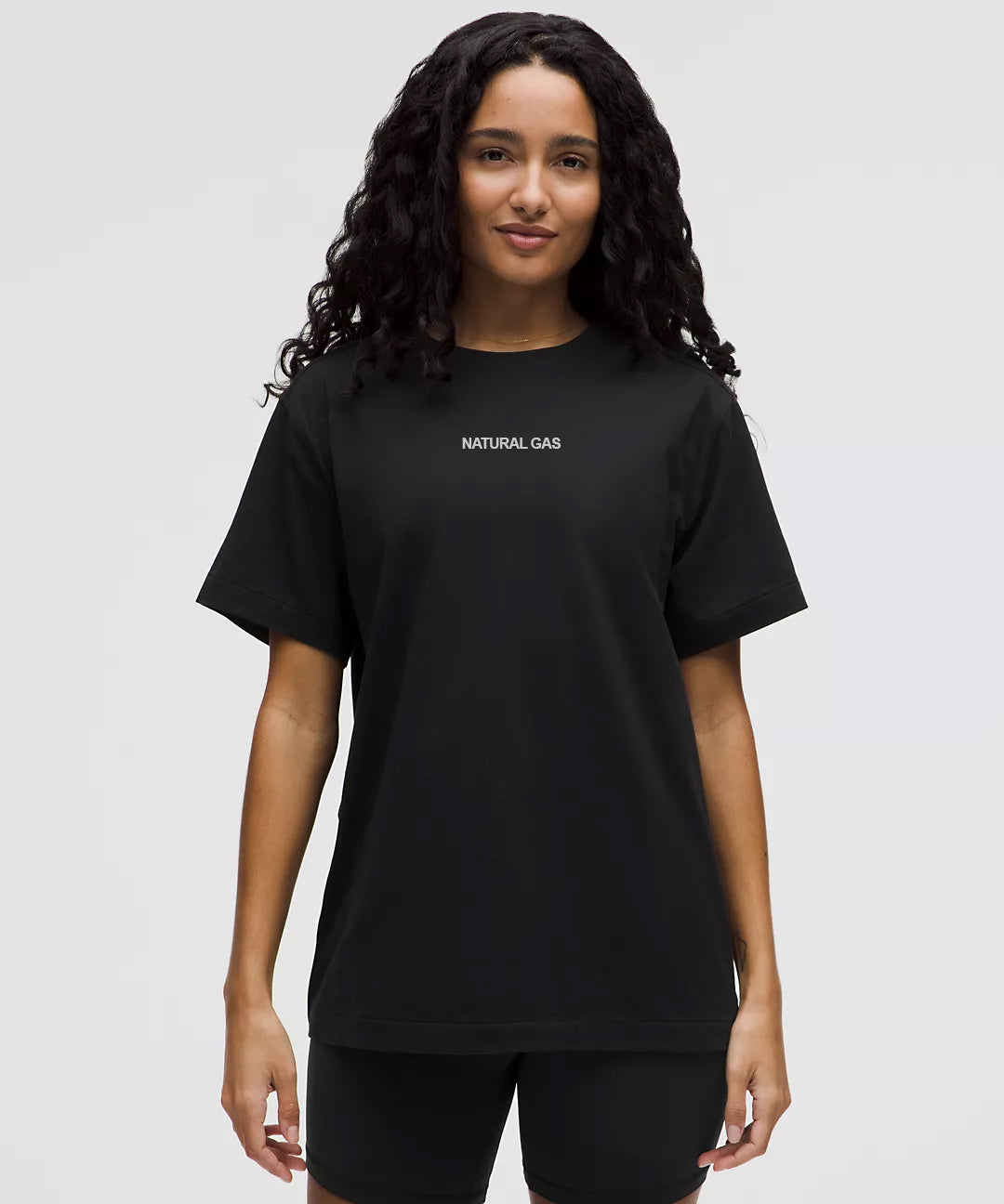 Women’s front view of black Natural Gas oversized T-shirt with minimalist white chest logo, casual athletic fit.