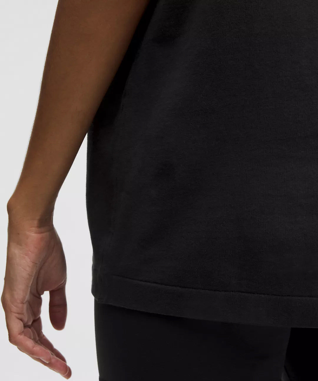 Close-up of Natural Gas women's black t-shirt hem, showcasing the clean stitch detail and relaxed fit for casual athletic wear.