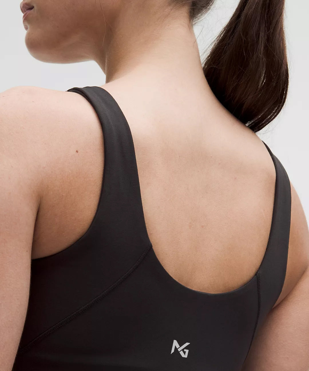 Close-Up Back View of Woman Wearing Black Natural Gas Tank Top – NG Logo Detail at Upper Back – Minimalist Activewear Branding
