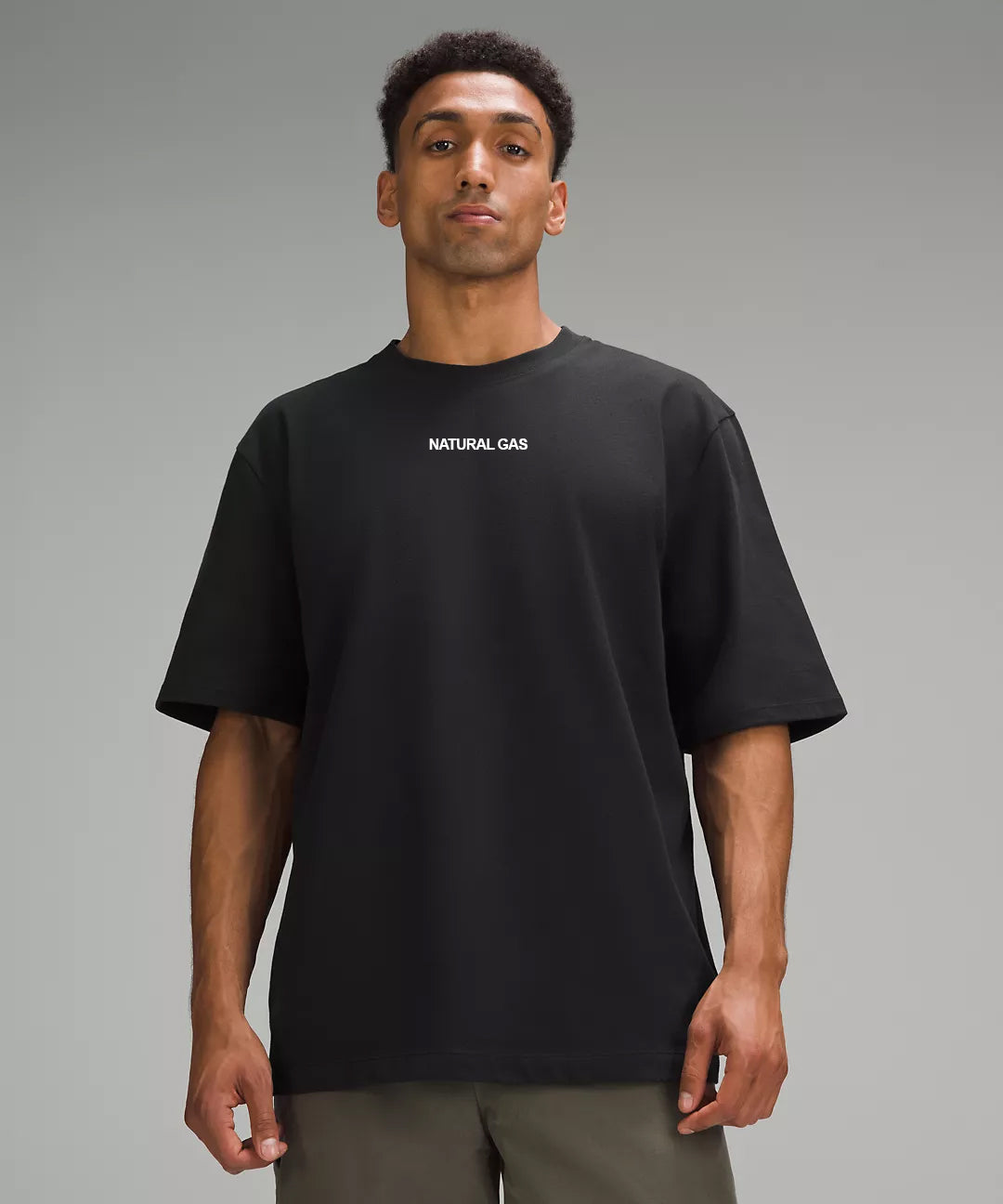 A man wearing a black crew neck t-shirt with a white 'Natural Gas' logo printed across the chest.